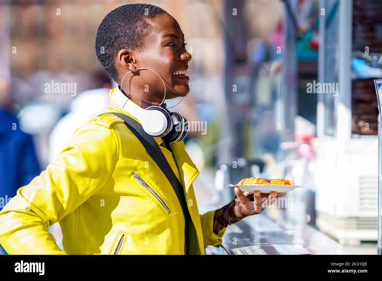 Donna sorridente che tiene un piatto di cibo al punto di concessione Foto Stock