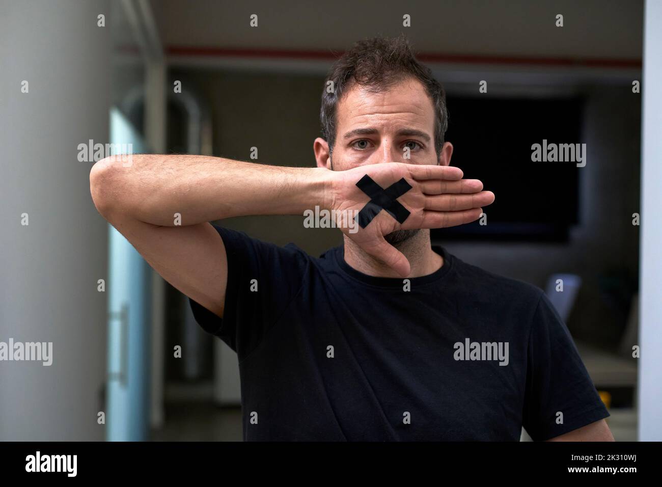 Uomo che ricopre la bocca con la mano a forma di croce Foto Stock