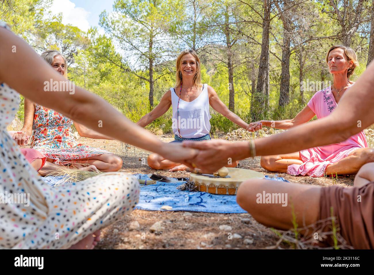 Felice donna matura con amici meditando di fronte all'albero Foto Stock