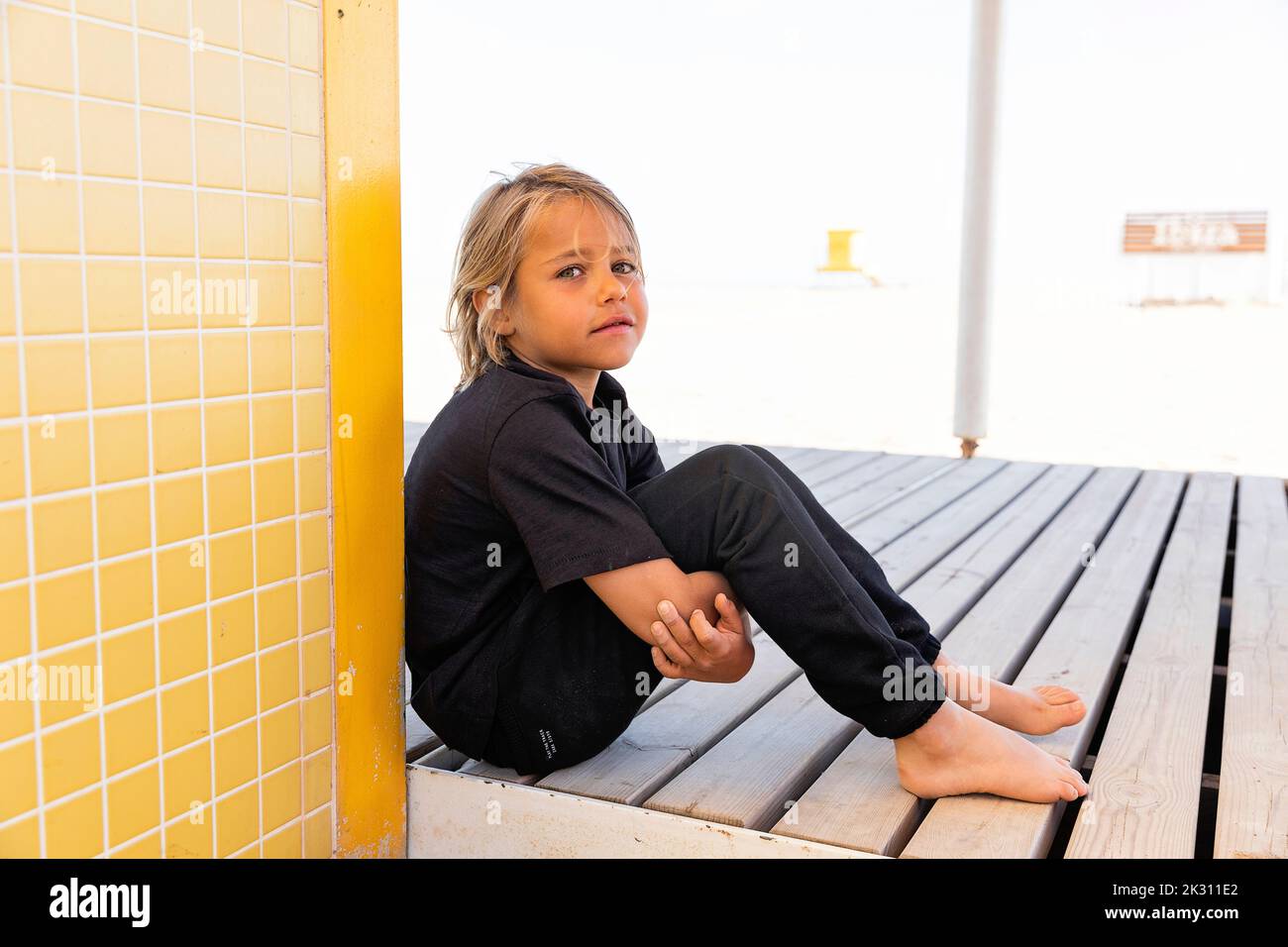Triste ragazzo biondo seduto su pavimento in legno Foto Stock