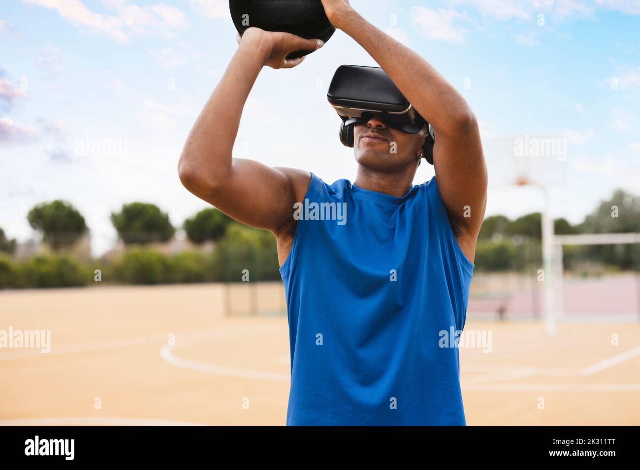 Giovane uomo che indossa il visore VR per lanciare il basket nel campo sportivo Foto Stock