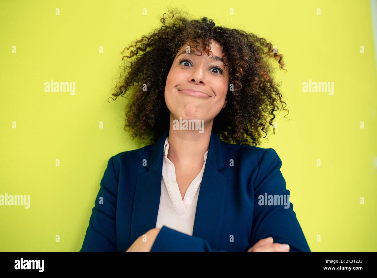 Donna d'affari matura che fa i volti davanti al muro Foto Stock