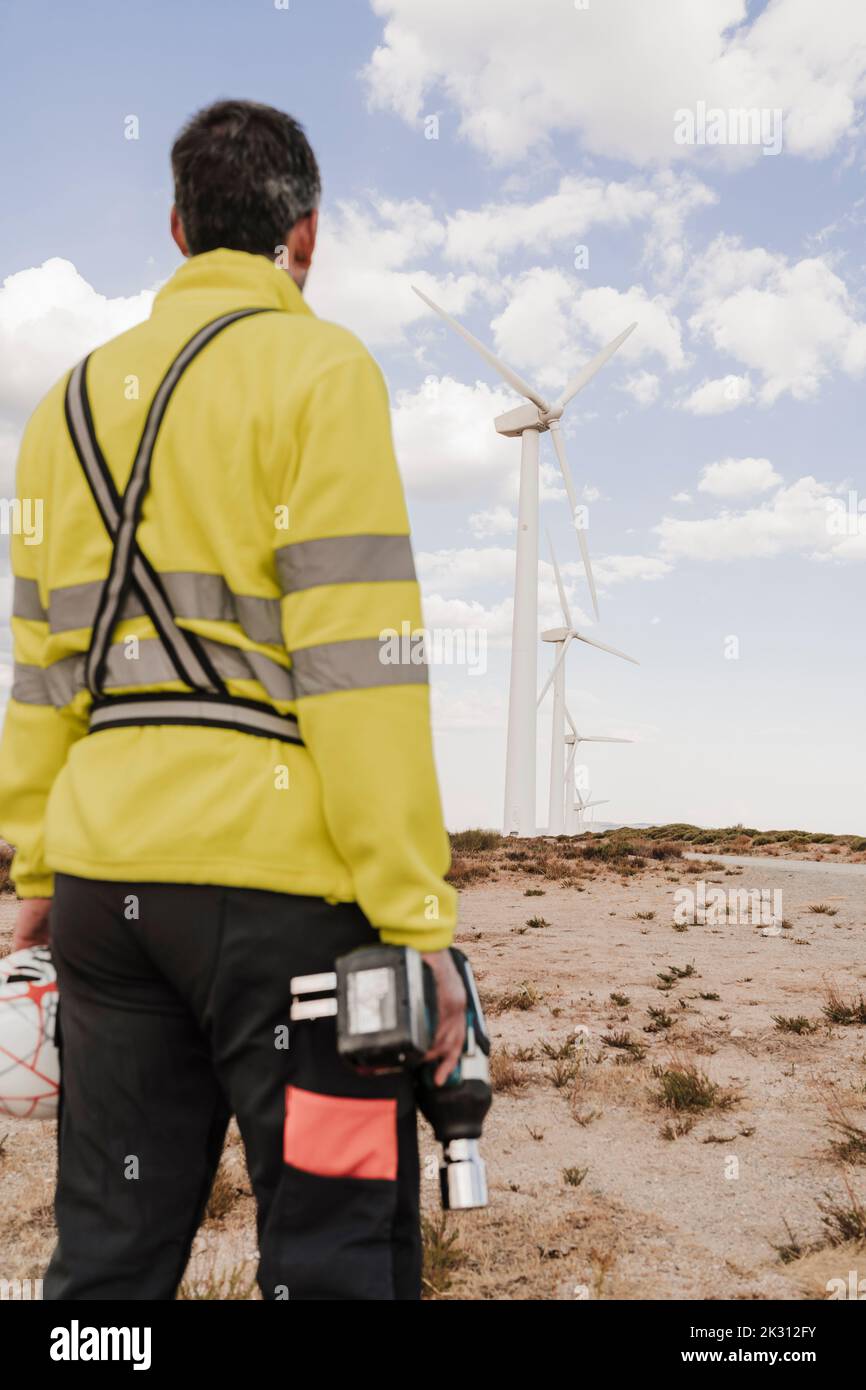 Tecnico con attrezzatura che guarda le turbine eoliche Foto Stock Tecnico con attrezzatura che guarda le turbine eoliche Foto Stock
