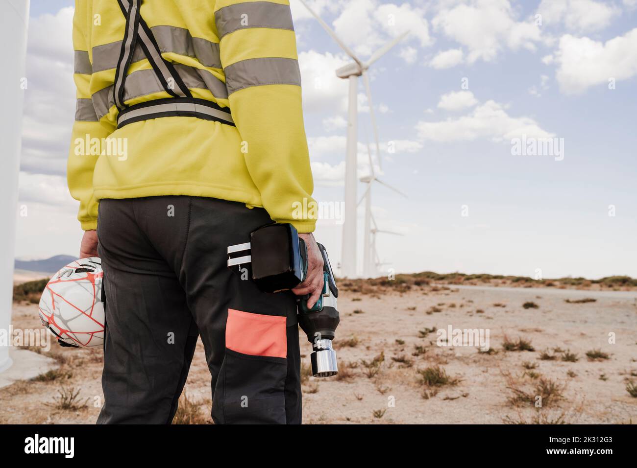 Tecnico con attrezzatura e casco in piedi presso la centrale eolica Foto Stock Tecnico con attrezzatura e casco in piedi presso la centrale eolica Foto Stock