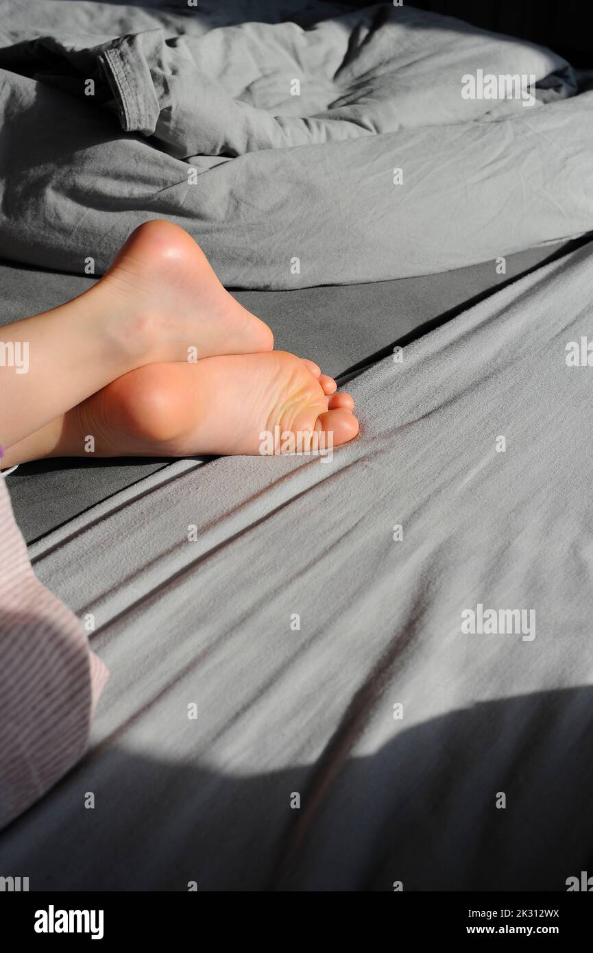 Ragazza sdraiata sul letto con le gambe incrociate Foto Stock
