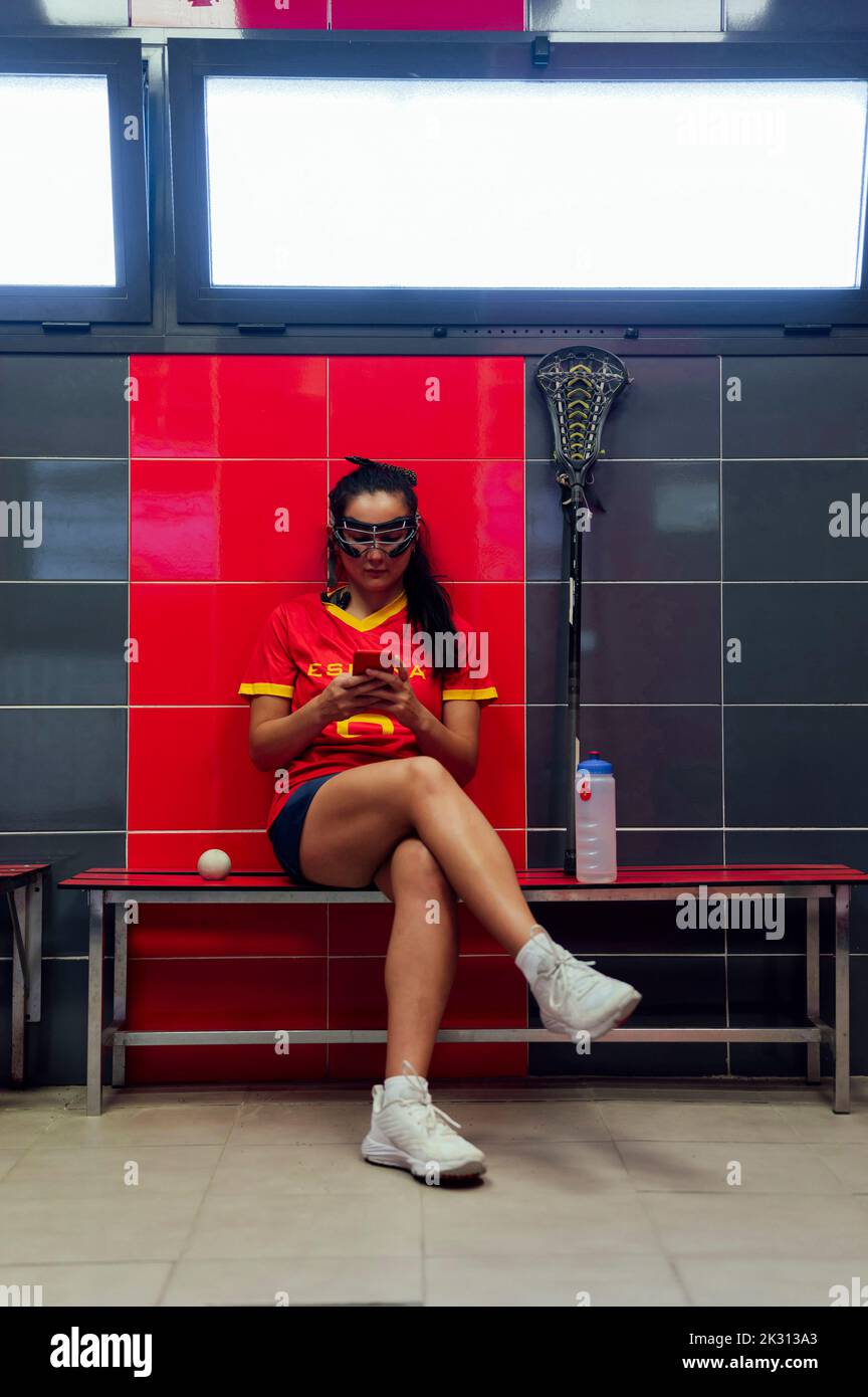 Giovane donna utilizzando il telefono cellulare in spogliatoio Foto Stock