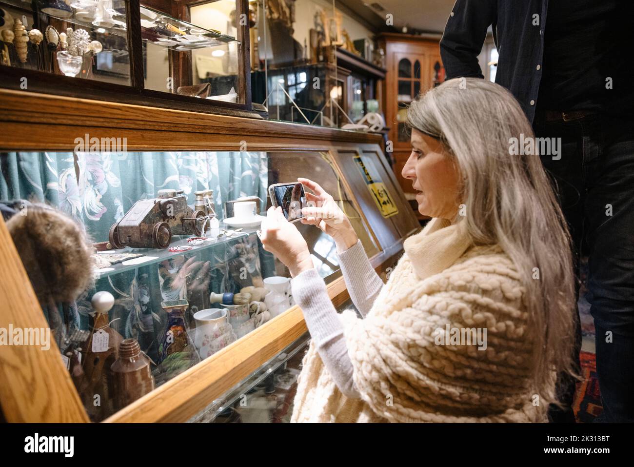 Donna che scatta una foto di un oggetto in un negozio di antiquariato Foto Stock