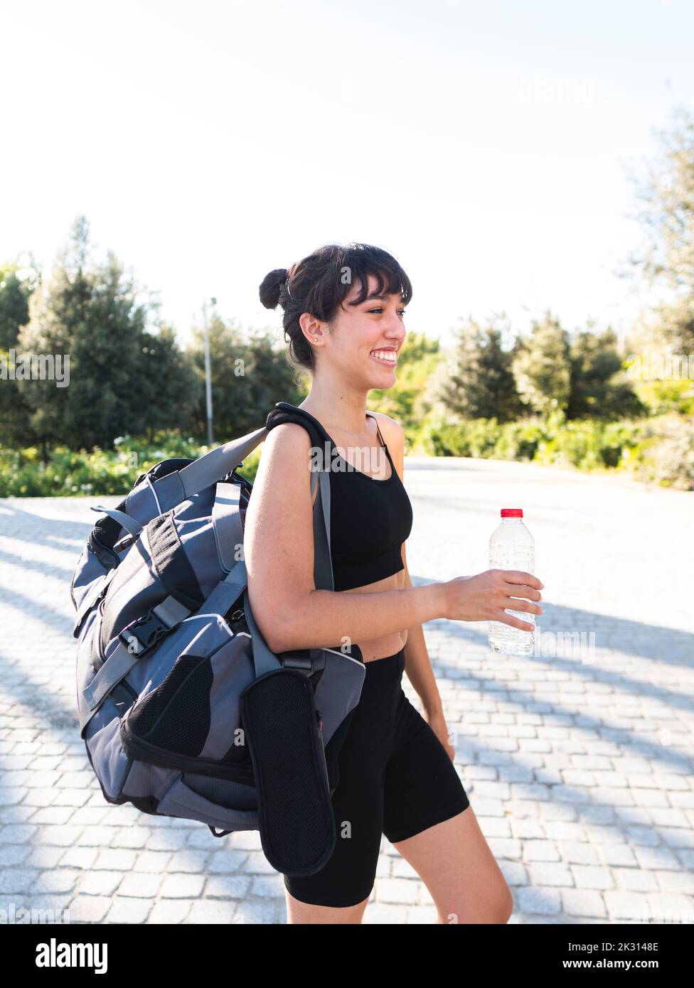 Felice giovane sportivo con borsa palestra a piedi Foto Stock