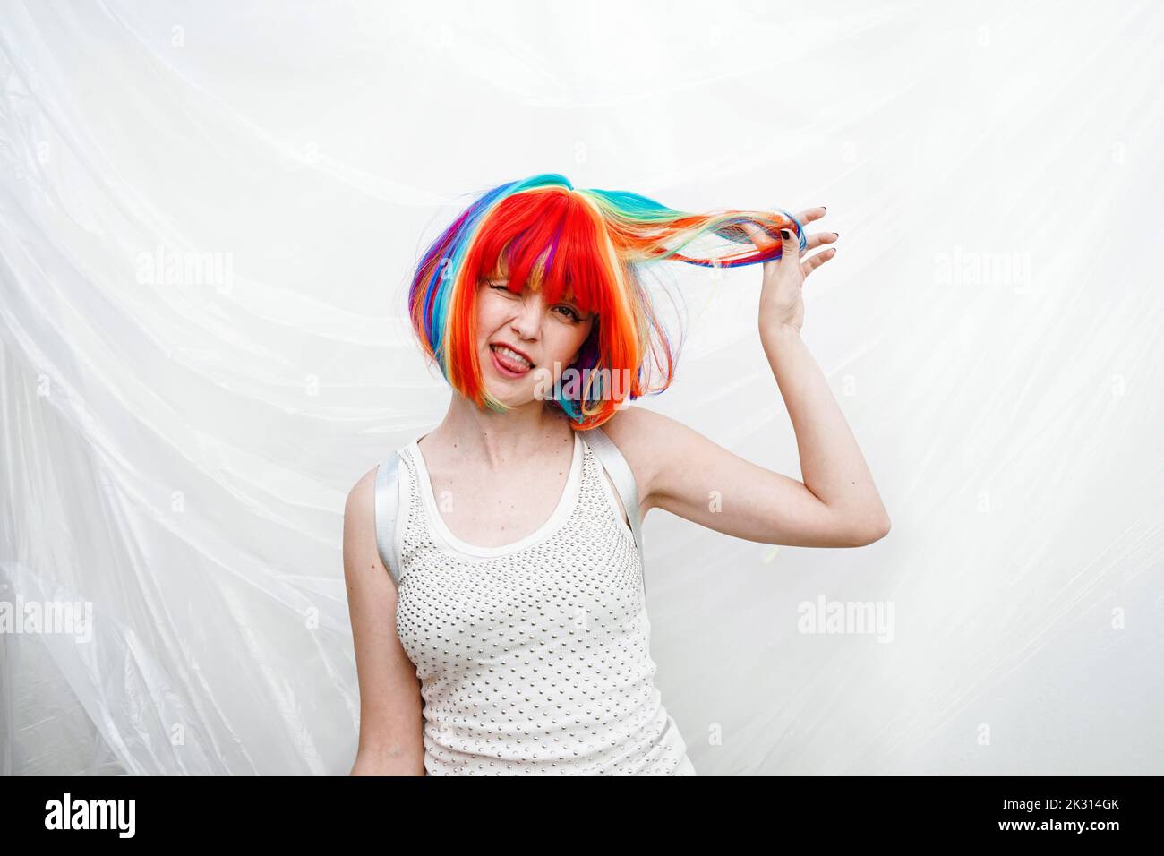 Donna giocosa con mano nei capelli da sfondo di plastica Foto Stock
