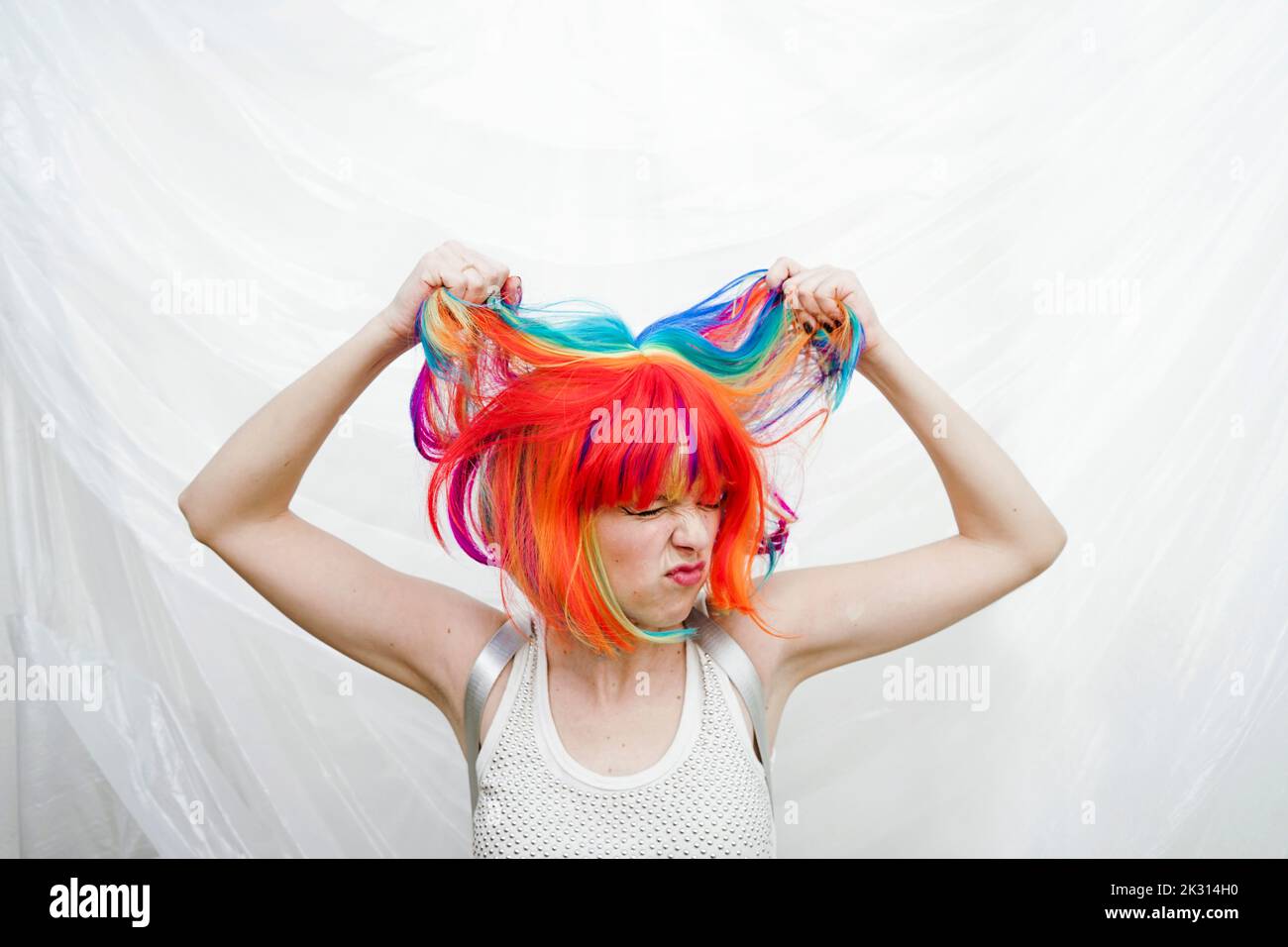 Donna che tira i capelli di fronte a sfondo di plastica Foto Stock
