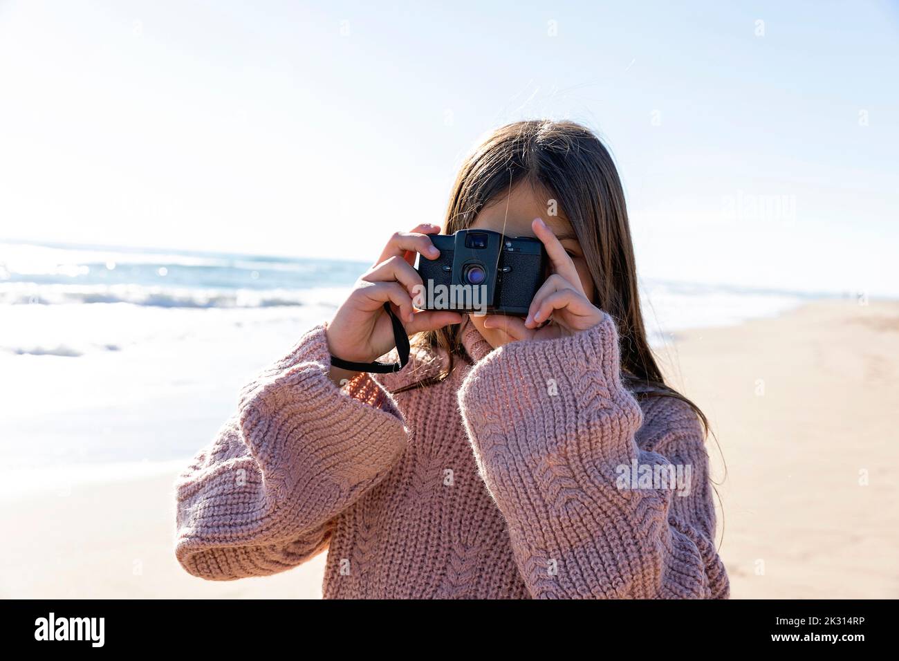Ragazza con fotocamera che scatta foto in spiaggia Foto Stock