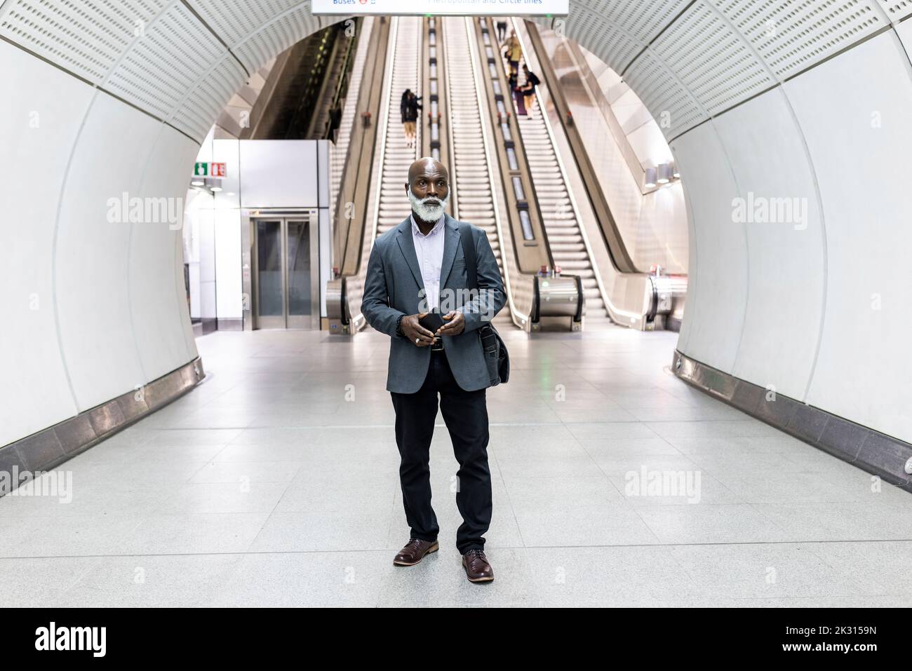 Uomo d'affari premuroso con telefono cellulare alla stazione della metropolitana Foto Stock
