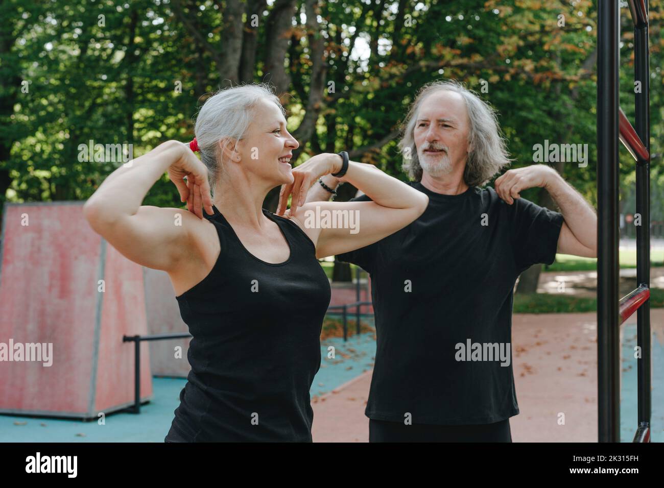 Coppia sorridente che fa esercizio di riscaldamento nel parco Foto Stock