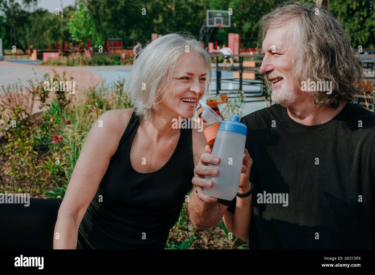 Felice coppia bere acqua nel parco Foto Stock