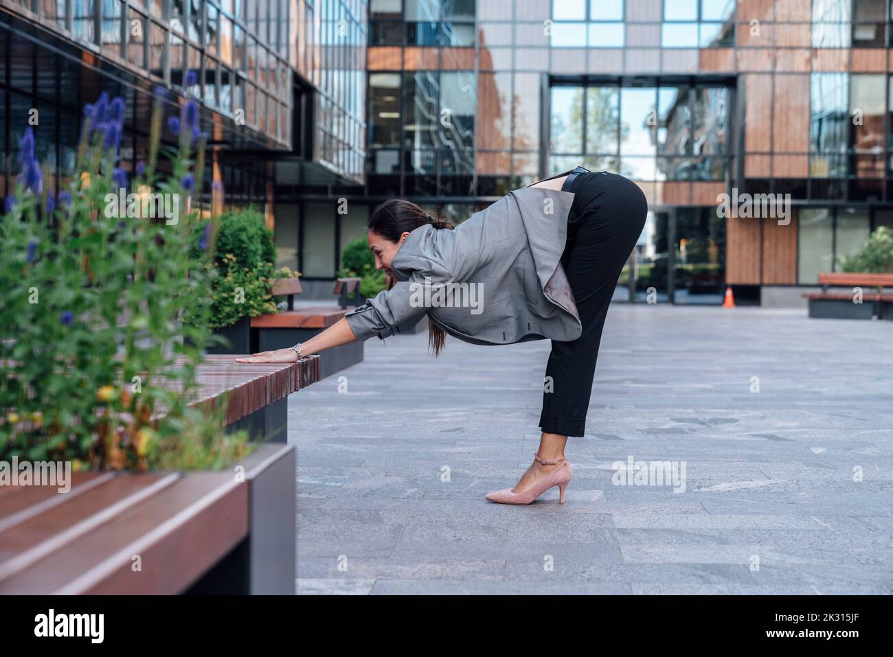 Donna d'affari che pratica esercizi di stretching presso il parco dell'ufficio Foto Stock