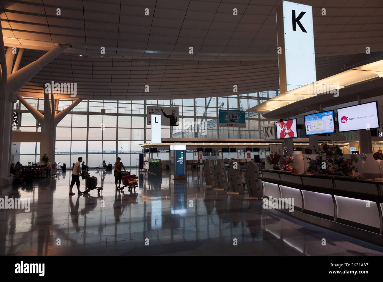 I viaggiatori spingono i carrelli dei bagagli al Terminal dell'Aeroporto Internazionale di Haneda, Tokyo, Giappone Foto Stock