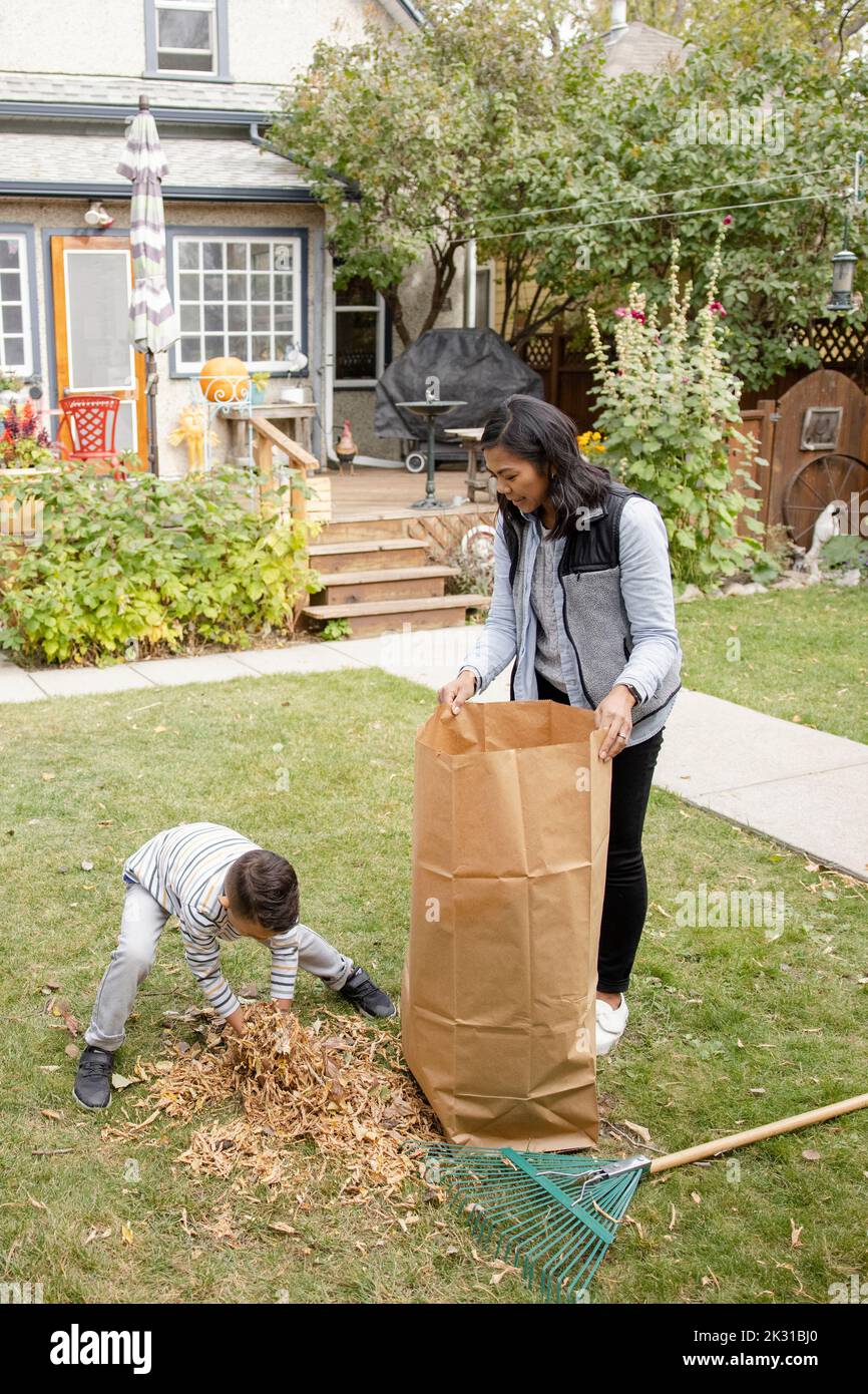 Il ragazzo riordinare le foglie in cortile Foto Stock
