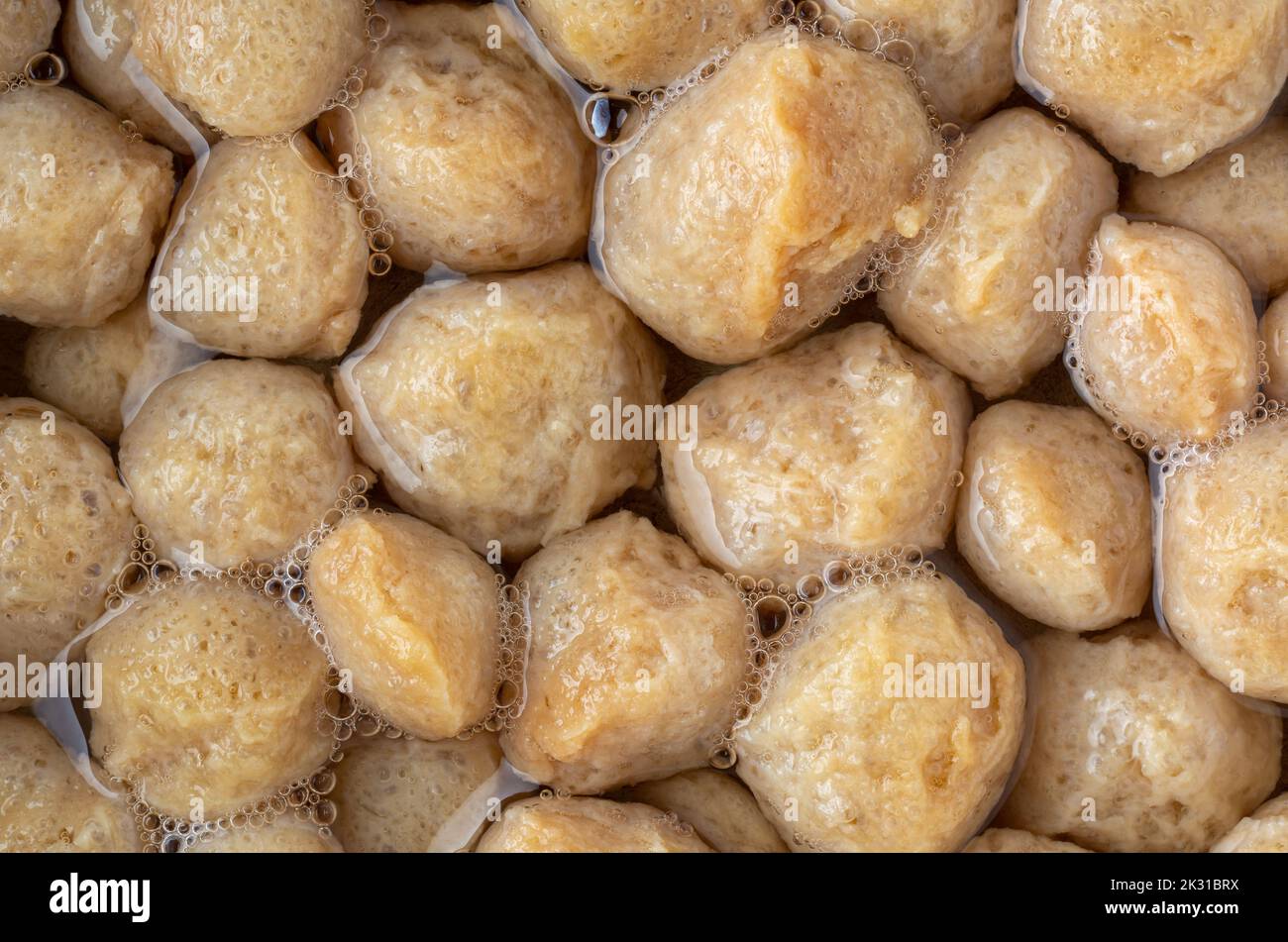 primo piano di carne di soia non cotta imbevuta in acqua bollita per diventare grassa o sbarazzarsi dell'odore pungente, processo di cottura di soia ricca di proteine vegetariane Foto Stock