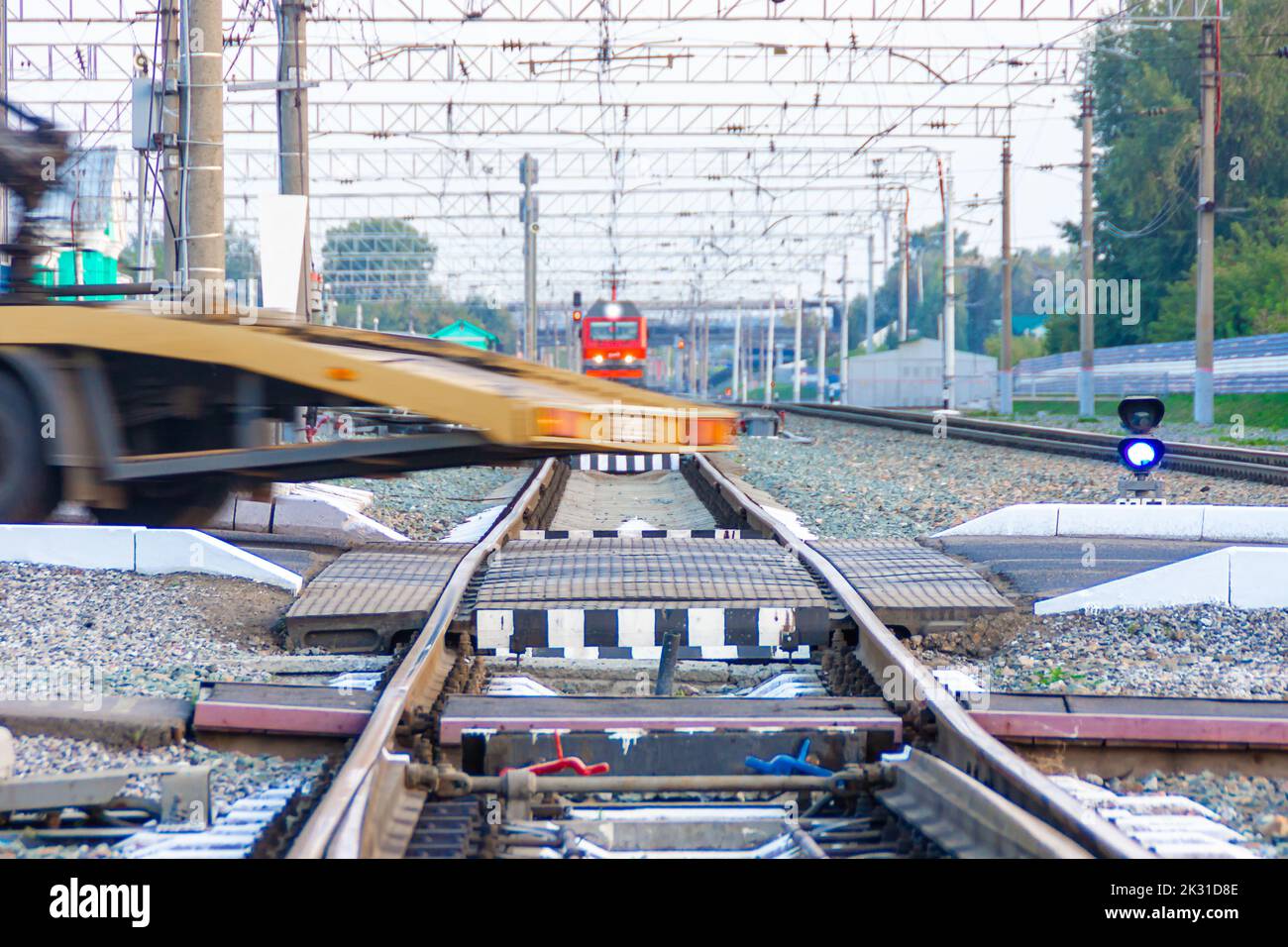 Il carro attrezzi ha superato un incrocio ferroviario di fronte a un treno in avvicinamento, con messa a fuoco selettiva Foto Stock