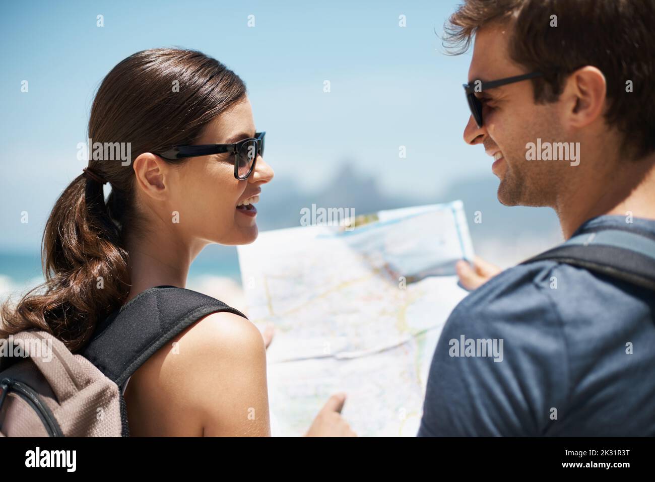 Vi ho detto che dovremmo andare così: Una giovane coppia che guarda una mappa mentre si trova in piedi su una spiaggia. Foto Stock