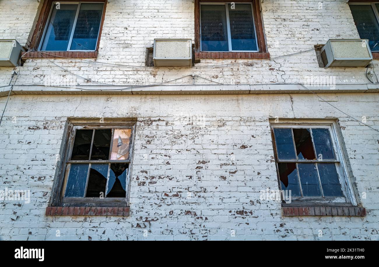 Finestre e condizionatori d'aria rotti sulle pareti di mattoni bianchi di un hotel abbandonato Foto Stock