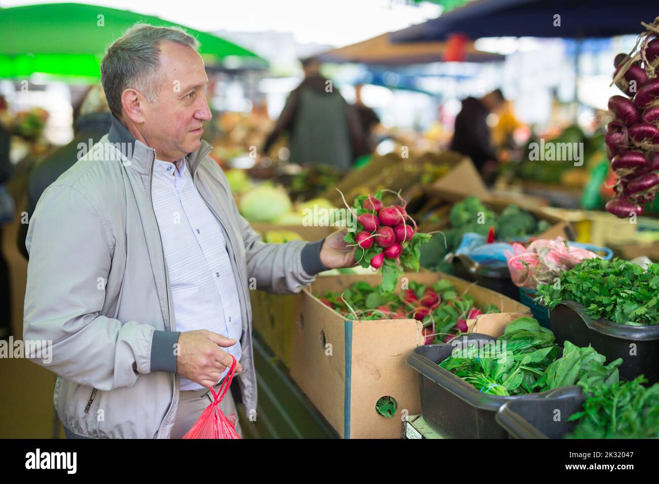 Uomo di mezza età che acquista radish Foto Stock