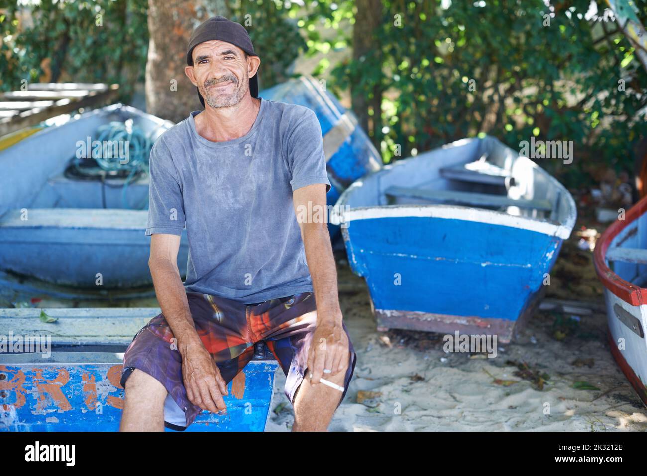 La pesca è la mia vita. Ritratto di un pescatore dall'aspetto aspro seduto su una barca da pesca. Foto Stock