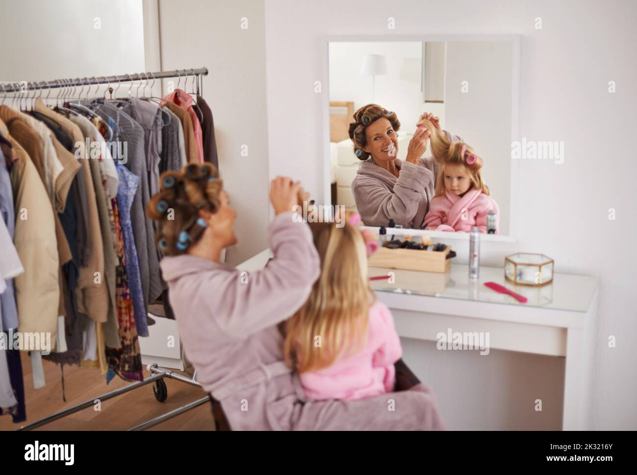 Lascia spazzolare i capelli. Una giovane madre che prepara la figlia per un evento importante. Foto Stock