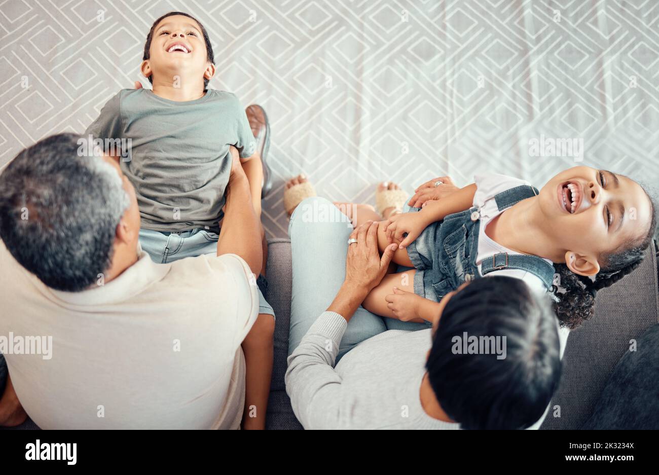 Famiglia, figli e nonno ridono, felici e divertenti su un divano dall'alto, giocando in un soggiorno. Foto Stock
