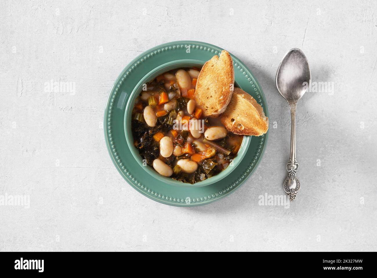 Ribollita fatta in casa, zuppa di fagioli toscani con ciabatta di segale leggera in ciotola verde. Vista dall'alto, spazio copia Foto Stock