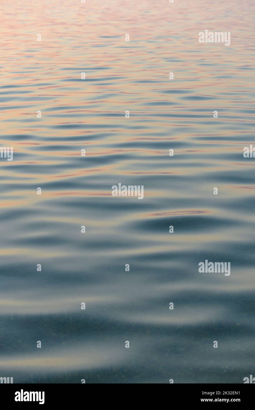 Onde di mare calme con riflesso del tramonto Foto Stock