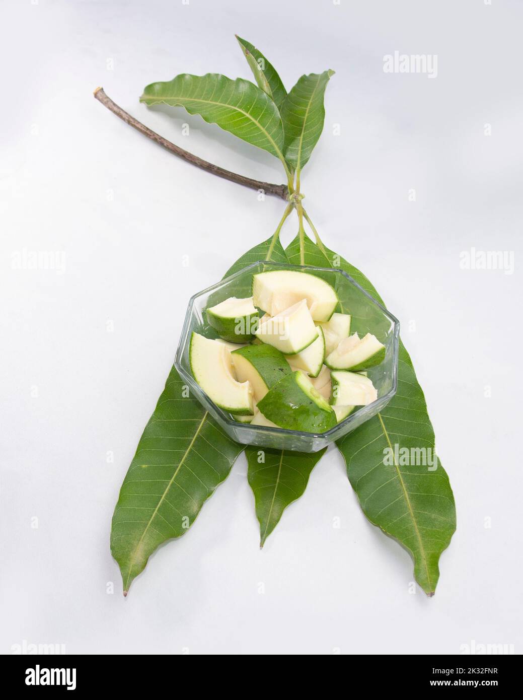 fette di mango verde crudo sulle foglie. Foto Stock