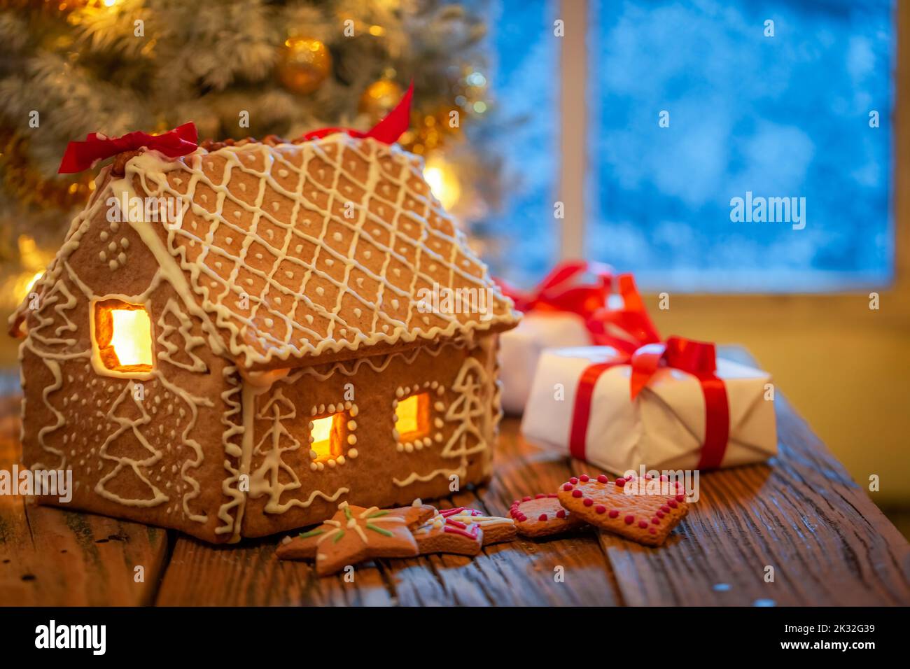 Gingerbread cottage e presenta sotto albero di Natale con luce. Sfondo per Natale. Foto Stock