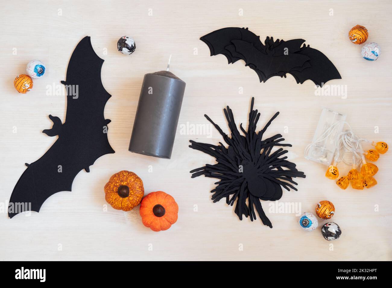 Decorazione di Halloween festa con zucche di carta pipistrelli e ragni, ghirlanda, dolci, caramelle, candele nere su tavola di legno. All'interno Halloween festa Foto Stock