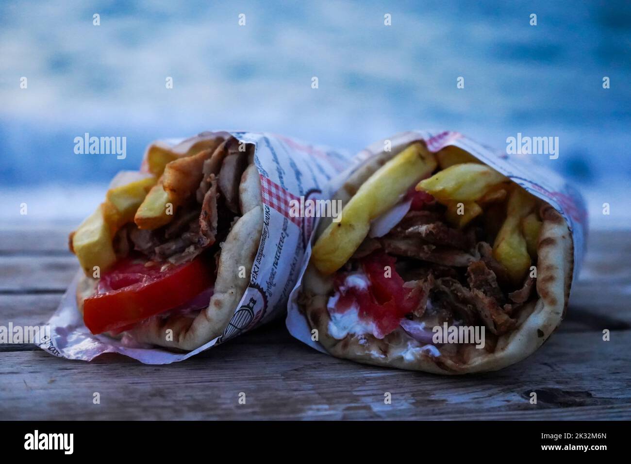 un paio di gustosi gyros di maiale greco avvolti su un tavolo di legno. Foto Stock