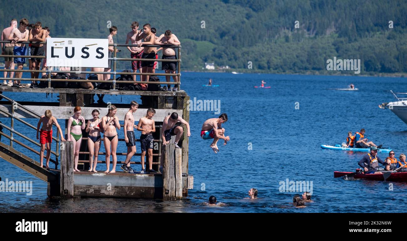 Le persone amano l'estate all'aperto al Luss sul Loch Lomond, Scozia, saltando, nuotando nelle fresche acque del lago. Foto Stock