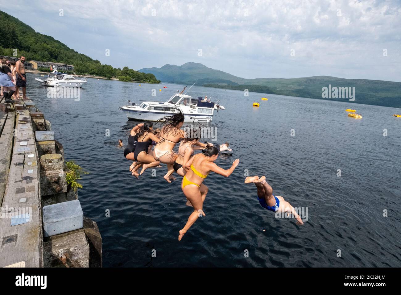 Le persone amano l'estate all'aperto al Luss sul Loch Lomond, Scozia, saltando, nuotando nelle fresche acque del lago. Foto Stock