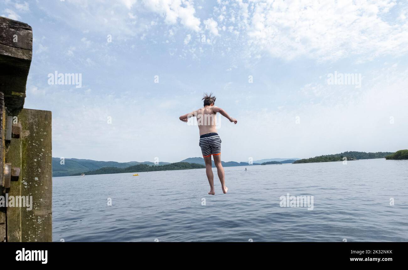 Le persone amano l'estate all'aperto al Luss sul Loch Lomond, Scozia, saltando, nuotando nelle fresche acque del lago. Foto Stock