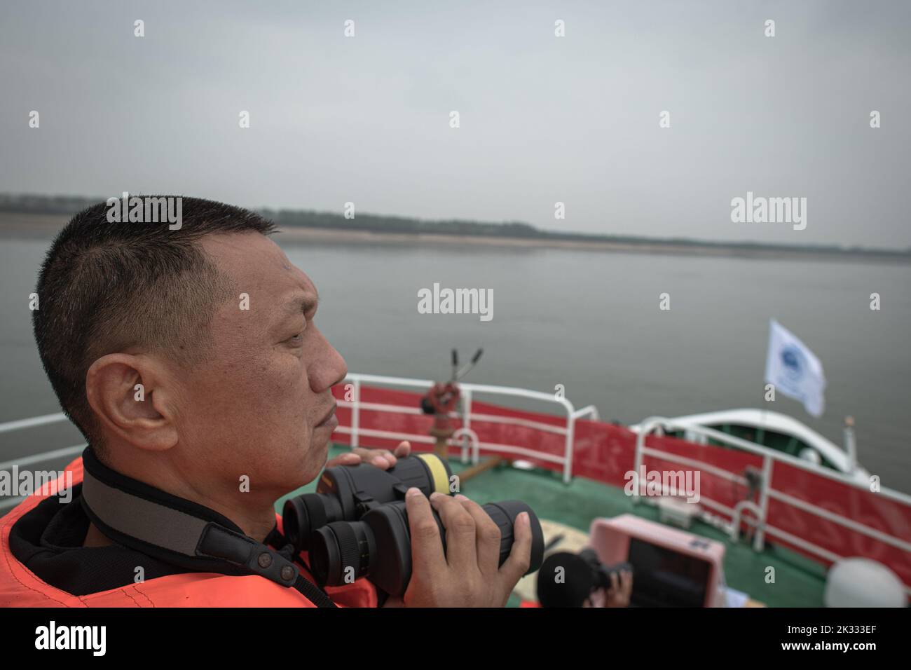 (220924) -- WUHAN, 24 settembre 2022 (Xinhua) -- Un ricercatore utilizza un paio di binocoli per condurre lavori di monitoraggio durante una spedizione scientifica sulle focene senza finezze di Yangtze nella sezione Shishou del fiume Yangtze, provincia di Hubei della Cina centrale, 23 settembre 2022. Lunedì la Cina ha lanciato un'indagine scientifica sulle focene senza fini di Yangtze, una specie iconica nel fiume più lungo del paese, Yangtze, con l'obiettivo di formulare un piano di protezione più mirato per la specie. Organizzato dal bacino del fiume Yangtze amministrazione della pesca sotto il Ministero dell'Agricoltura e degli Affari rurali, la spedizione Foto Stock