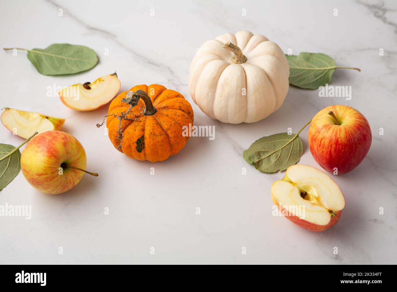 Piccole zucche e mele su una superficie leggera Foto Stock