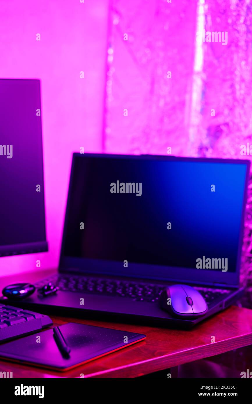 Luogo di lavoro di un grafico e di un retoucher creativo. Tablet grafico, smartphone e computer con luce al neon. Spazio di lavoro di design creativo Foto Stock
