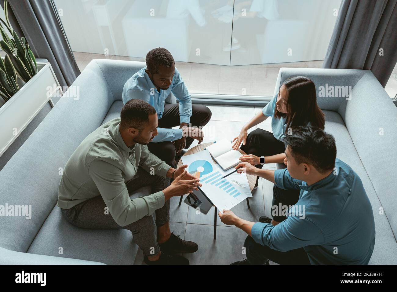 Gruppo di uomini d'affari multietnici che lavorano insieme sul progetto mentre si siedono in un ufficio moderno Foto Stock