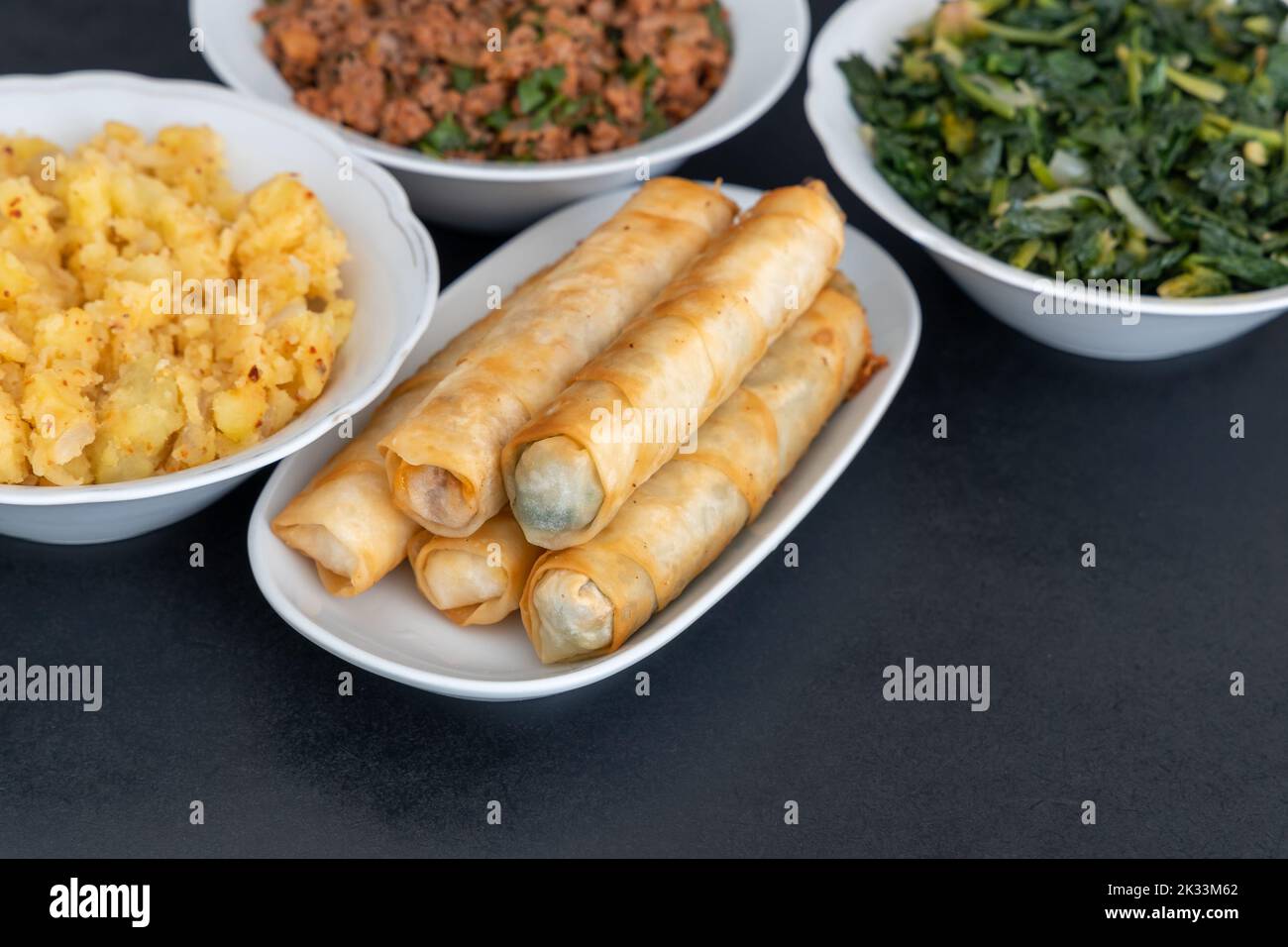 Rotoli a forma di cigar turco. Tradizionale Borek, Burek, cotto, grigliato fresco panini alimentari primavera su sfondo nero. Copia spazio, Vista superiore. Foto Stock