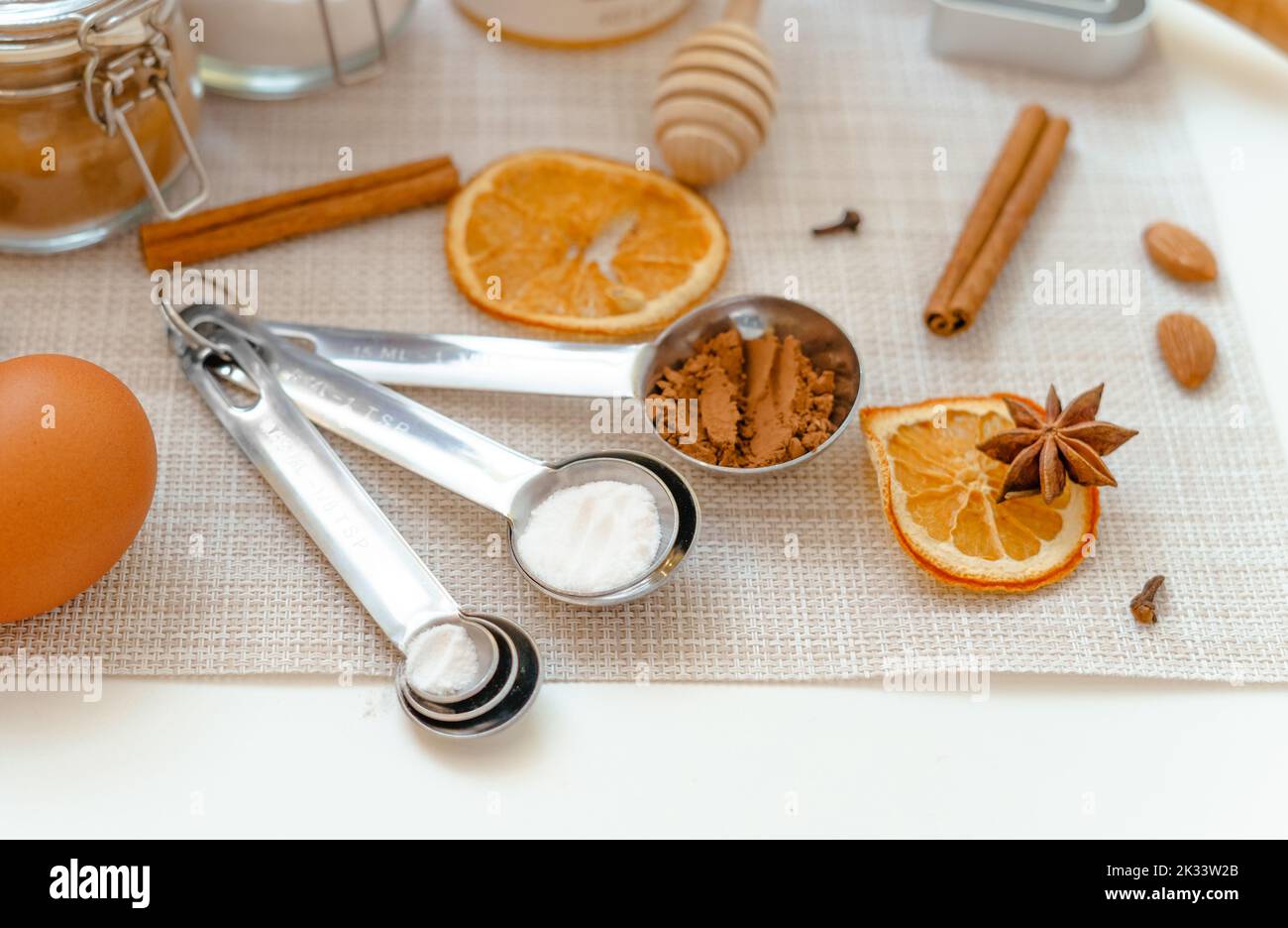 misurini con lievito in polvere, farina e cacao in polvere su un tavolo bianco con utensili da cucina Foto Stock