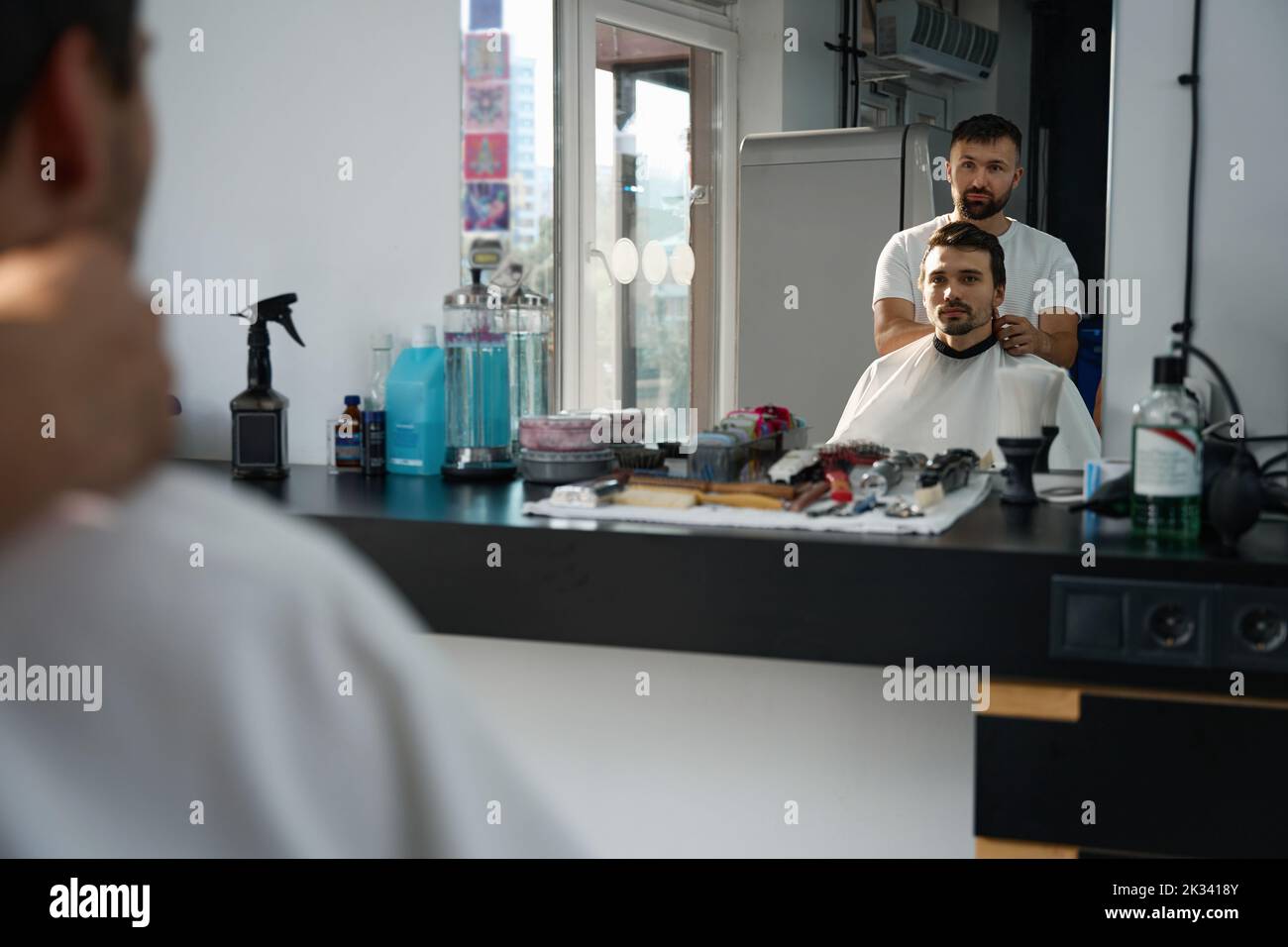 Parrucchiere addetto salone e cliente guardando il loro specchio di riflessione Foto Stock