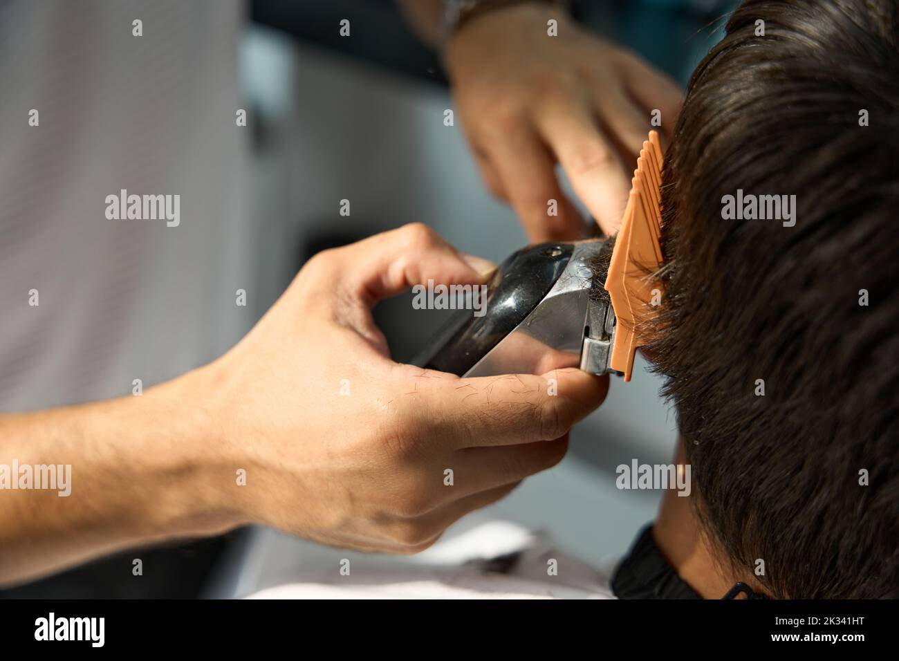Specialista esperto di capelli che usa il regolacapelli per tagliare i capelli dell'uomo Foto Stock