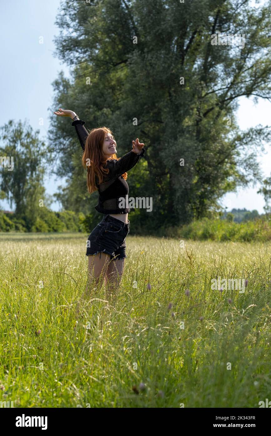 Giovane donna che gode della natura, in erba alta, vicino alla natura, prato, Landlust, Alta Baviera, Baviera, Germania Foto Stock