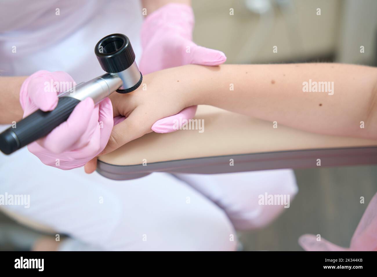 Le mani femminili del cosmetologist esaminano la mano del paziente con il dermatoscope Foto Stock