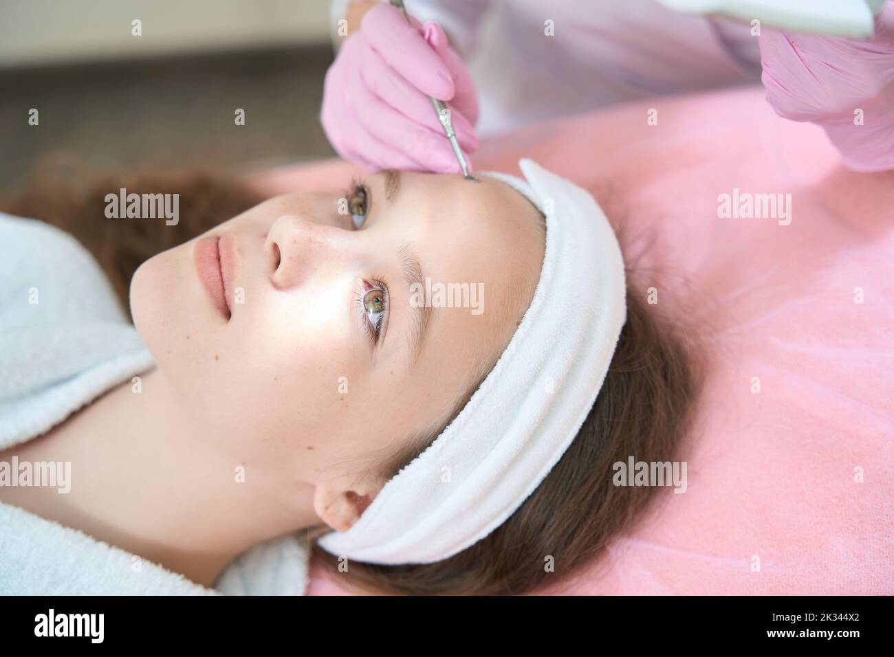 Primo piano del viso della ragazza mentre si pulisce uno cucchiaio in estetista Foto Stock