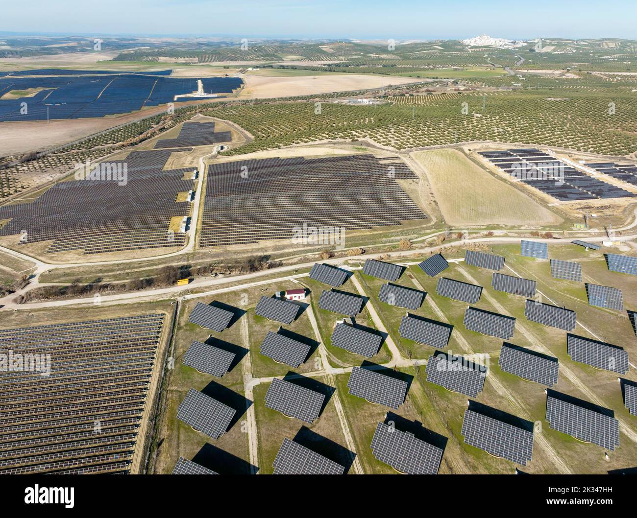 File di pannelli solari in un impianto fotovoltaico e la città di Espejo in lontananza, vista aerea, fucilato, provincia di Cordoba, Andalusia, Spagna Foto Stock